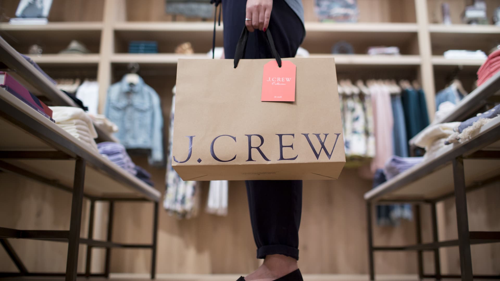 A women holding a bag poses for a photograph at J. Crew Group Inc.'s new women's store inside the International Finance Centre (IFC) mall in Hong Kong, China, on Thursday, May 22, 2014.