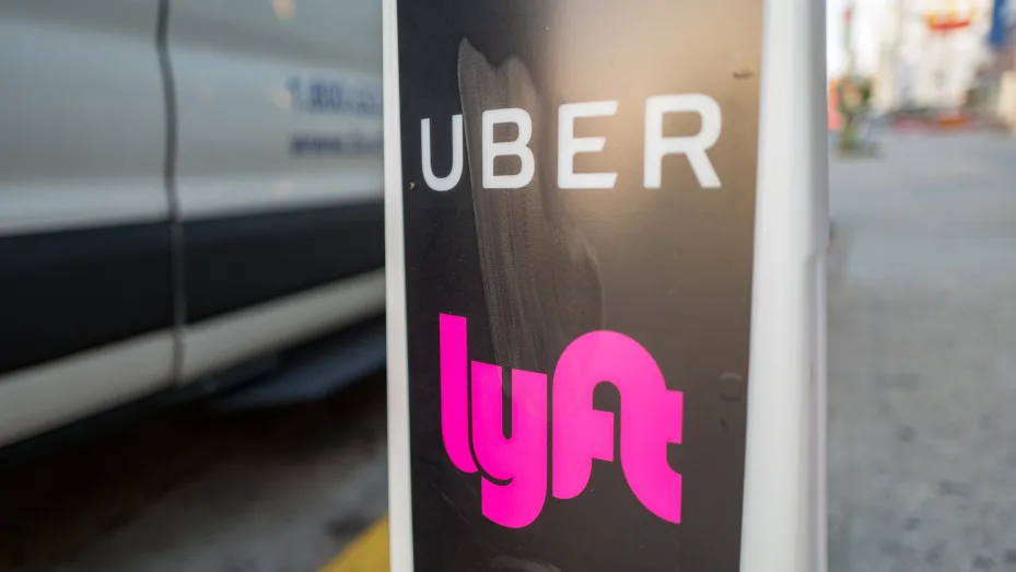 Close-up of vertical sign with logos for ride-hailing companies Uber and Lyft.