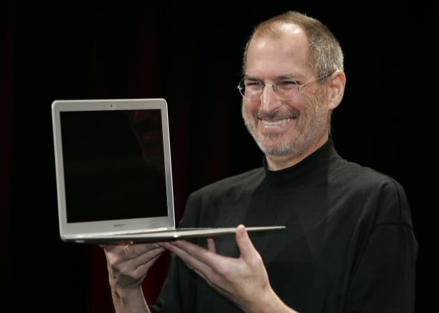 Apple CEO Steve Jobs smiles as he shows the MacBook Air