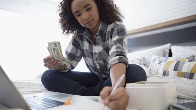 GP: Teenage girl managing personal finances at laptop on bed
