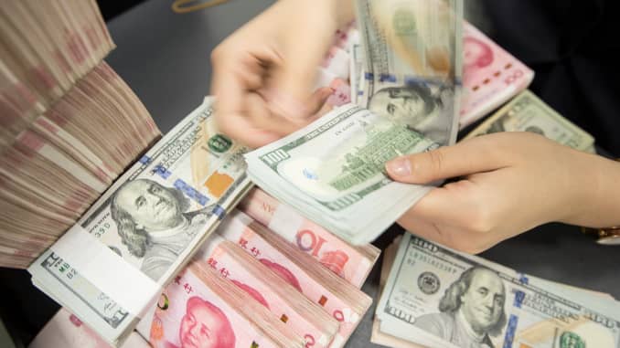 Un empleado del banco chino cuenta billetes de 100 yuanes y billetes en dólares estadounidenses en un mostrador bancario en Nantong, en la provincia oriental china de Jiangsu, el 6 de agosto de 2019.