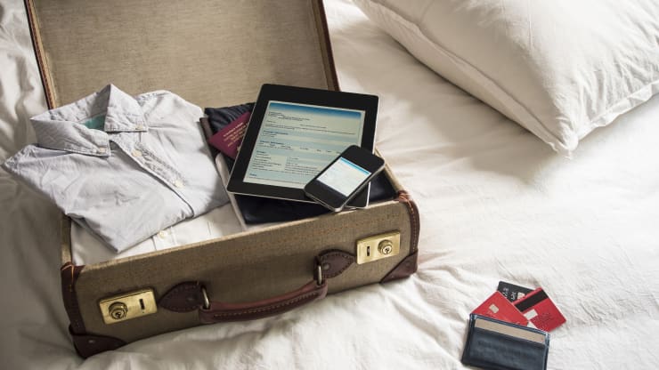 GP: Open suitcase on bed with digital tablet and mobile phone