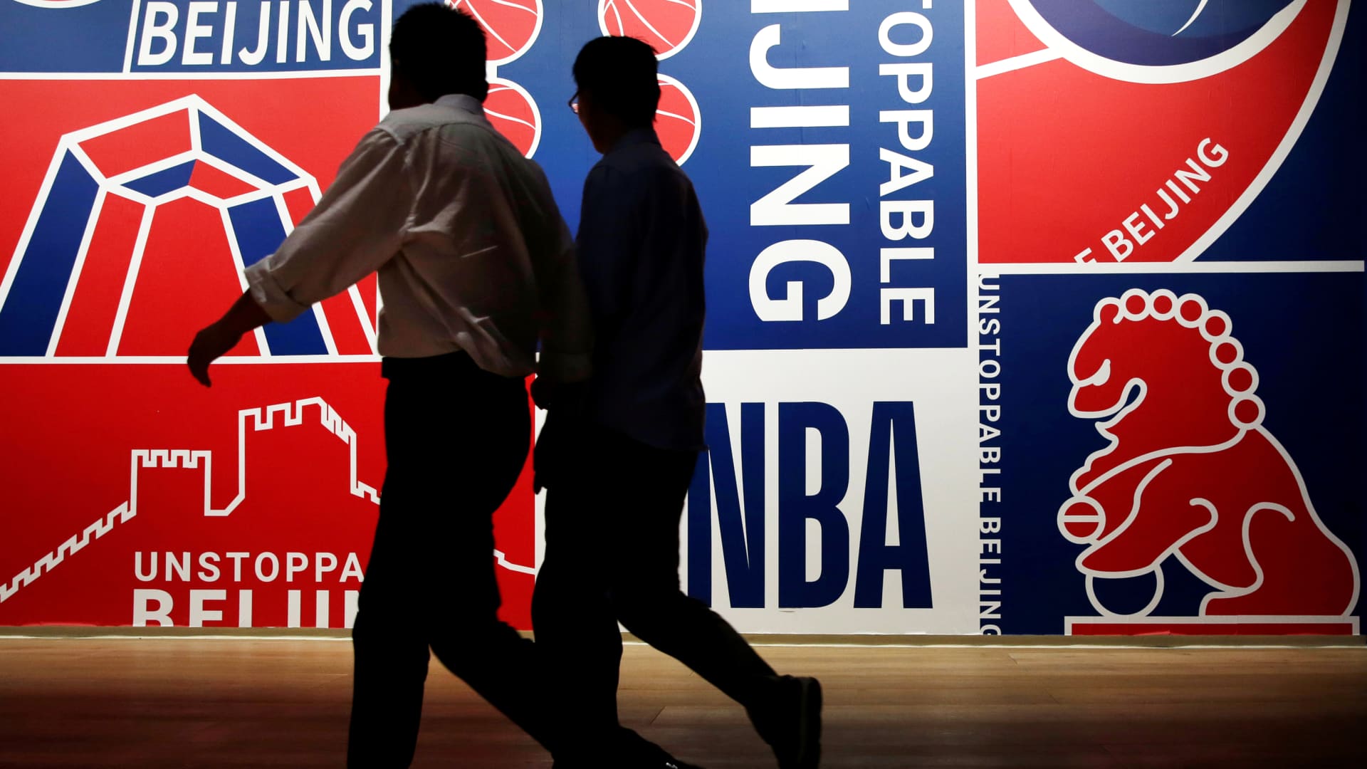 Men walk past a poster at an NBA exhibition in Beijing, China October 8, 2019.