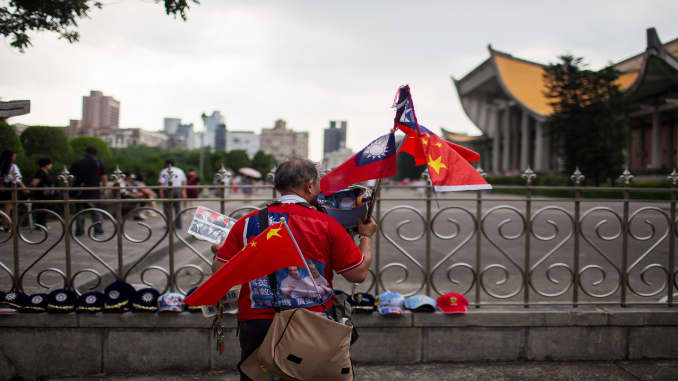 A vendor holds Taiwanese and Chinese national flags near the Sun Yat-sen Memorial in Taipei, Taiwan.
