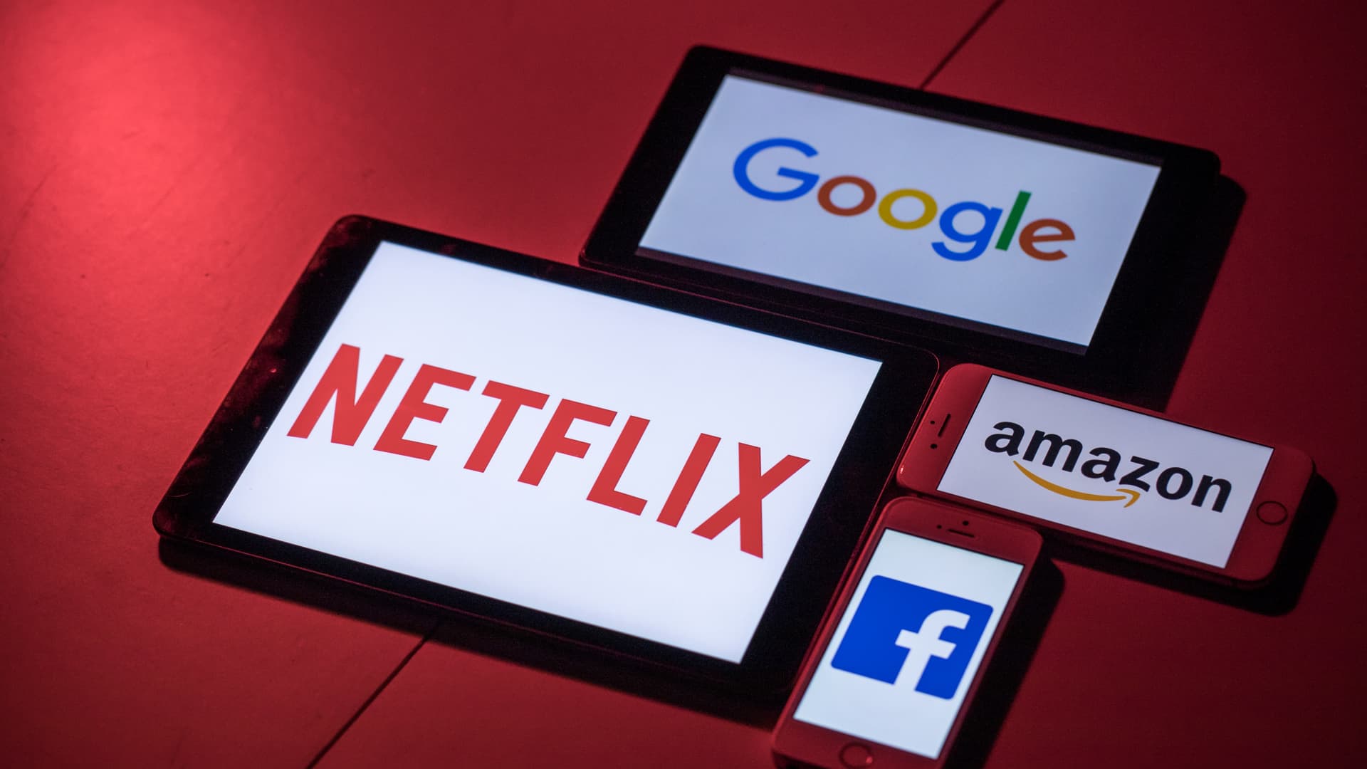 The logos for Facebook, Amazon, Netflix and Google, on smartphone and tablet devices