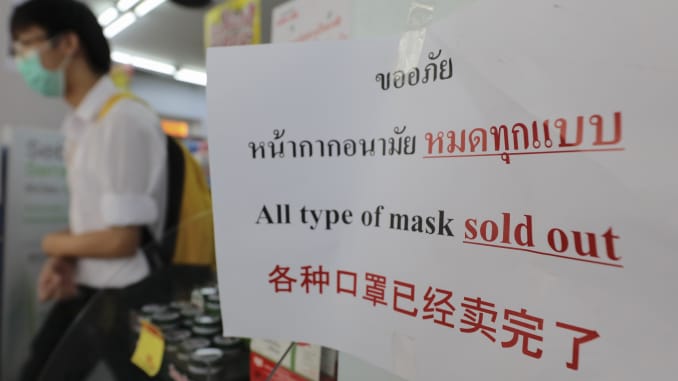 Un hombre enmascarado camina junto a un letrero que dice "Todo tipo de máscara ...