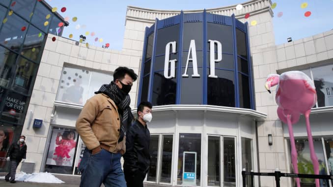 Men wearing face masks walk past a Gap store at a shopping area, as the country is hit by an outbreak of the new coronavirus, in Beijing, China February 7, 2020.
