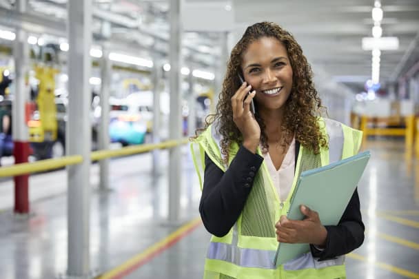 Portrait of manager using smart phone in car plant