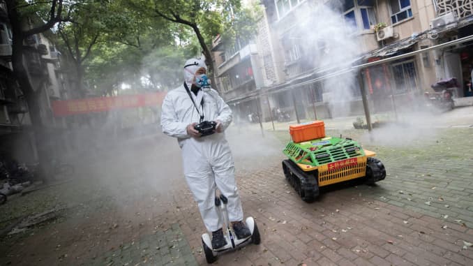 A volunteer operates a remote-controlled disinfection robot to disinfect a residential area amid the COVID-19 coronavirus outbreak in Wuhan in China's central Hubei province on March 16, 2020.
