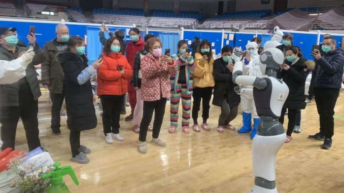 Coronavirus patients at a "smart field" hospital in Wuhan, China with a robot from CloudMinds.