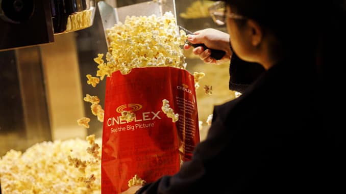An employee fills a bag of popcorn in the concessions area inside a Cineplex Cinemas movie theater.