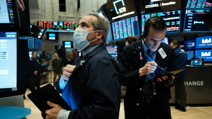Traders, some in medical masks, work on the floor of the New York Stock Exchange (NYSE) on March 20, 2020 in New York City. Trading on the floor will temporarily become fully electronic starting on Monday to protect employees from spreading the coronaviru