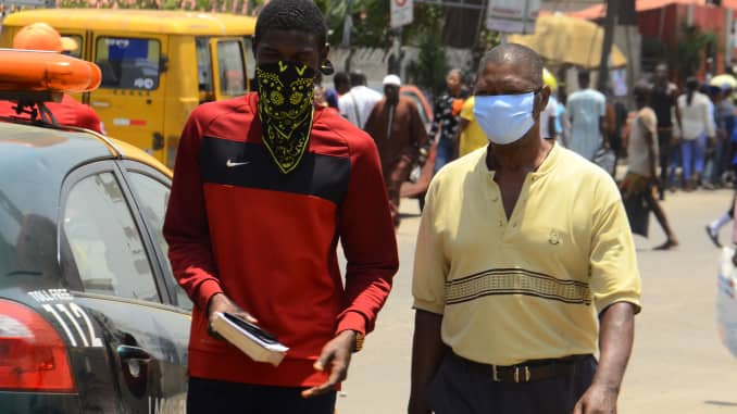 Commuters wearing a protective face masks walk on the street of Lagos, as a preventive measure against the spread of the new corona virus, COVIC-19, in Lagos, on March 26, 2020.