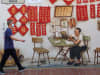 A man wearing a face mask walks past a mural in Chinatown in Singapore on April 1, 2020.