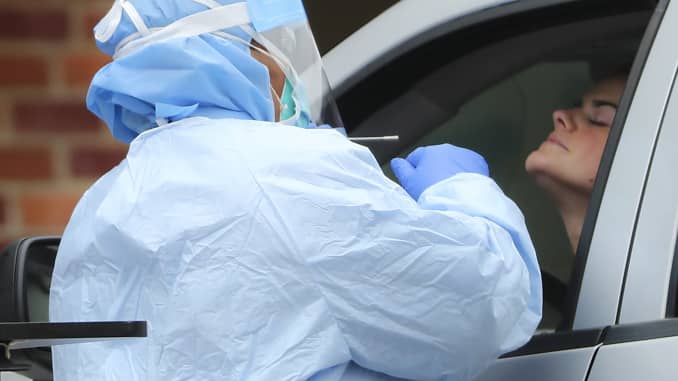 A health care professional swab tests a patient for coronavirus at drive-through testing outside the Emergency Room entrance at Beth Israel Deaconess Hospital in Milton, MA on March 30, 2020.