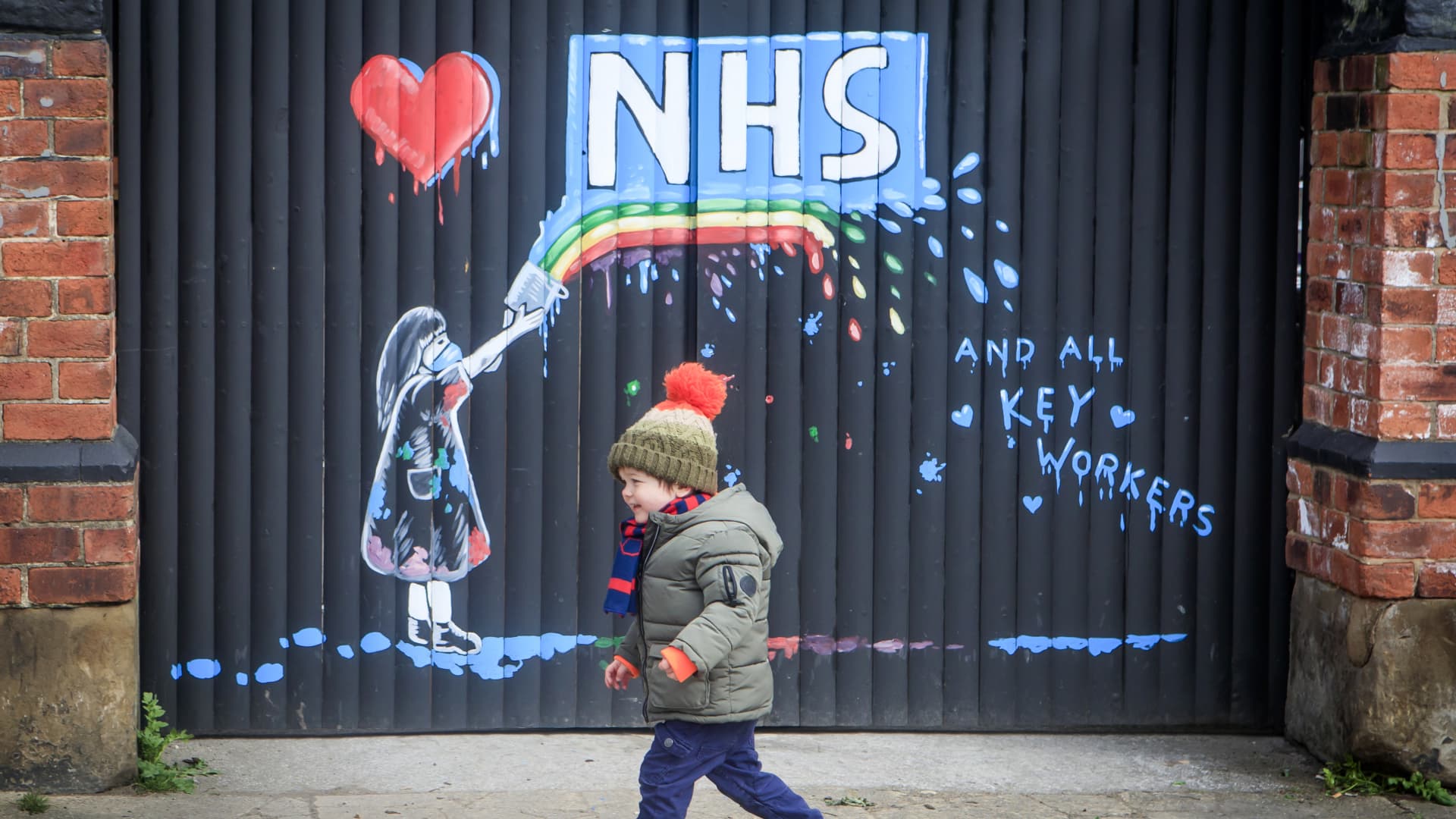 A boy runs past a mural supporting the NHS, by artist Rachel List, on the gates of the Hope & Anchor pub in Pontefract, Yorkshire, as the UK continues in lockdown to help curb the spread of the coronavirus.