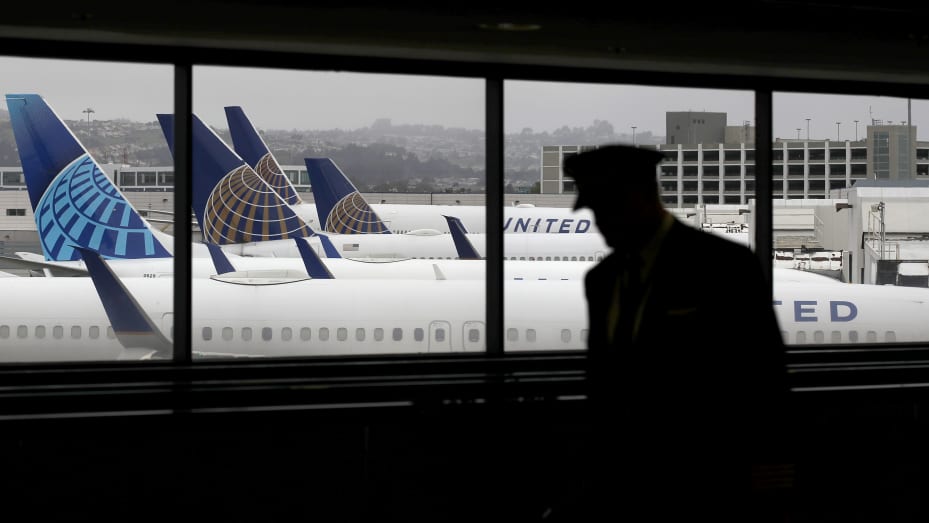 A pilot walks by United Airlines planes as they sit parked at gates at San Francisco International Airport on April 12, 2020 in San Francisco, California.