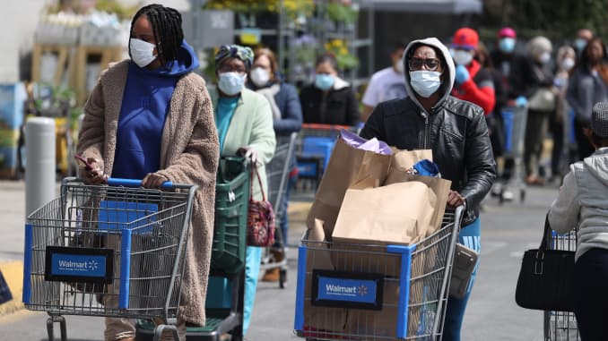 People wearing masks and gloves wait to enter a Walmart on April 17, 2020 in Uniondale, New York.