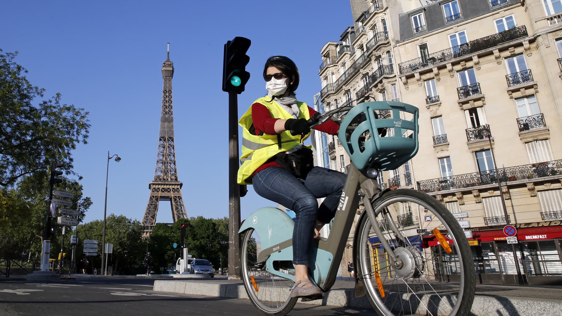 A woman wearing a protective mask rides her bicycle next to the Eiffel Tower on April 23, 2020 in Paris, France.