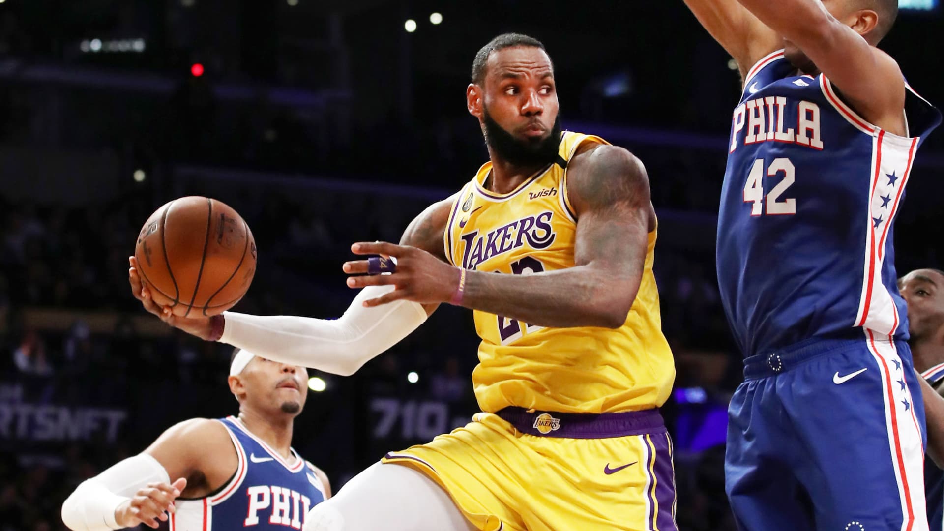 LeBron James of the Los Angeles Lakers passes the ball under the hoop against Al Horford #42 of the Philadelphia 76ers during the second half at Staples Center on March 03, 2020 in Los Angeles, California.