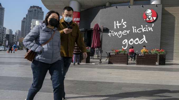 People wear facial mask walking past a KFC restaurant, which has resumed its outdoor dining area. For the COVID-19 epidemic situation is under control in China, most of shopping malls and stores are resuming business.