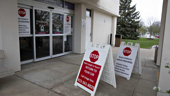 A sign directing patients with a cough or fever to return to their vehicle and call a triage phone line stands outside an entrance to Rochelle Community Hospital in Rochelle, Illinois, U.S., on Tuesday, April 14, 2020.