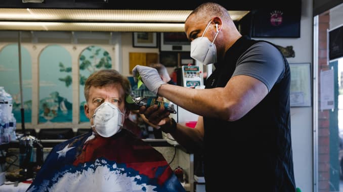 A stylist wearing a protective mask cuts a customer's hair at a barbershop in Atlanta, Georgia, U.S., on Monday, April 27, 2020.