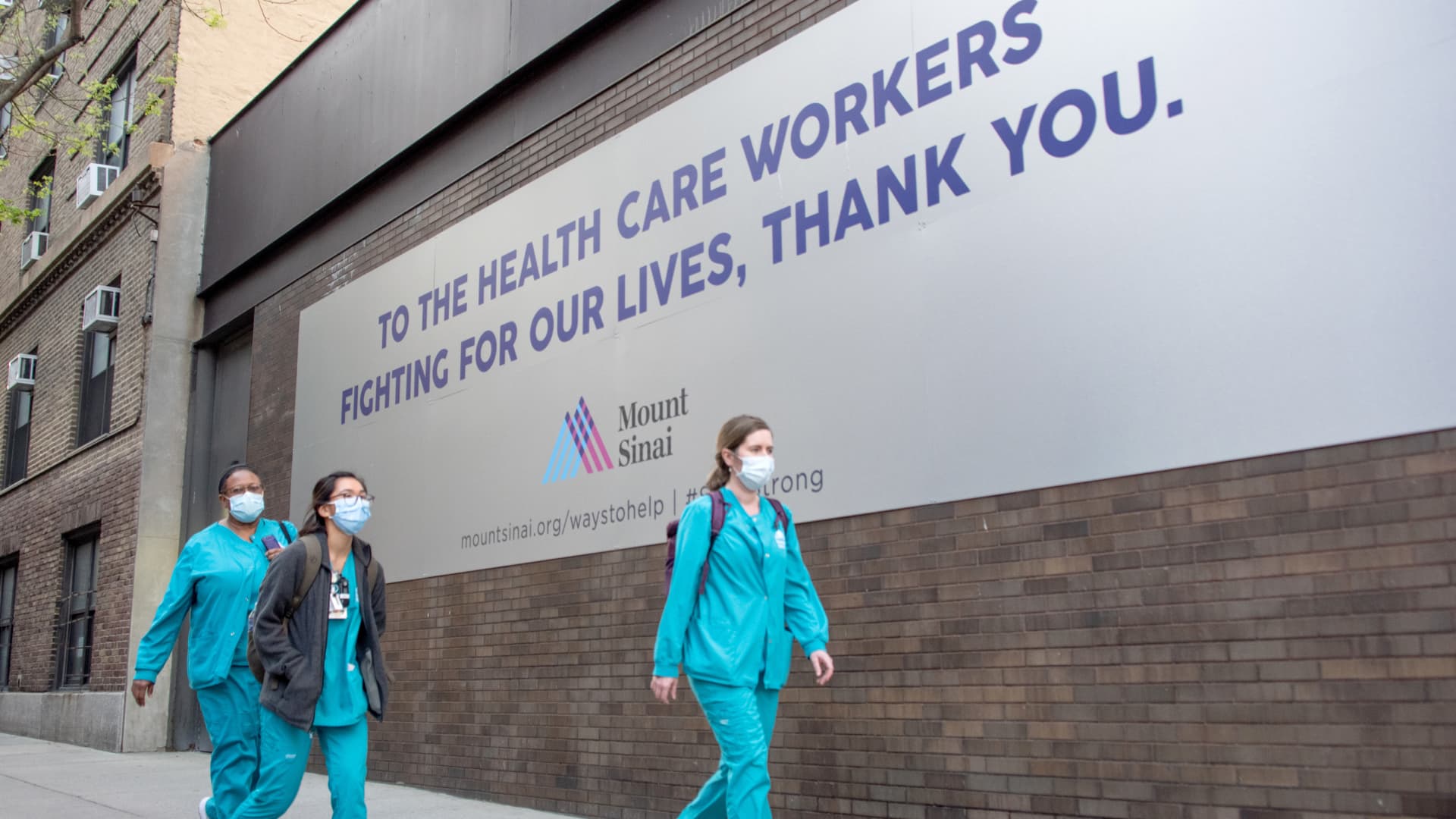 Medical workers wearing masks walk past a 'Thank You' sign outside of Mount Sinai Hospital amid the coronavirus pandemic on May 3, 2020 in New York City.