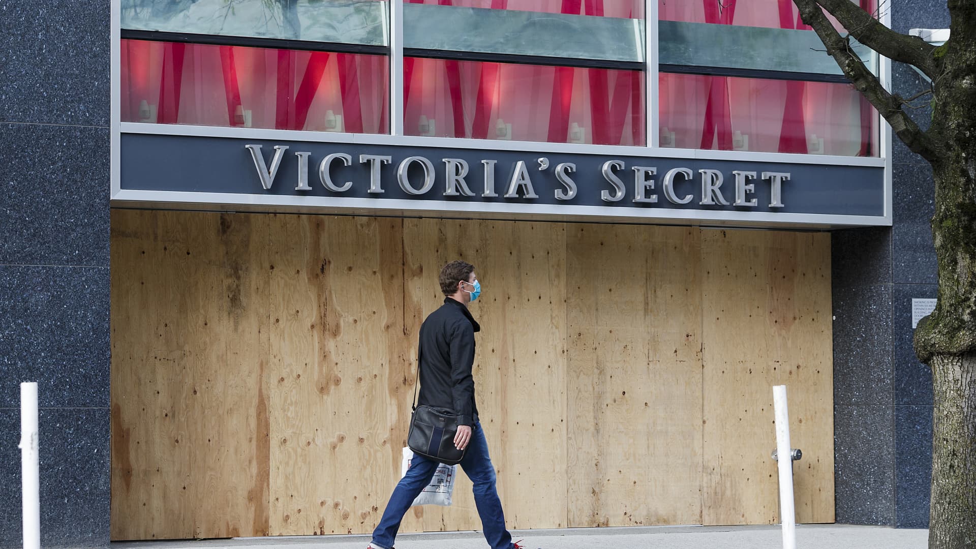A pedestrian walks past a Victoria's Secret storefront closed and boarded up on Robson Street during the COVID-19 crisis on April 17, 2020 in Vancouver, Canada.