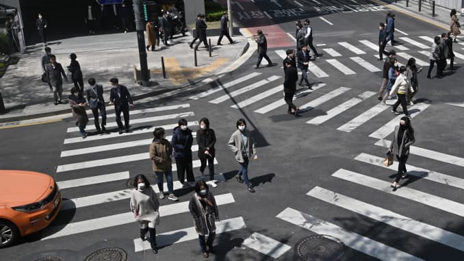 Pedestrians wearing face masks cross the road in Seoul on April 23, 2020.