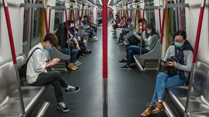 People wearing face masks, amid concerns of the COVID-19 coronavirus, commute on a train in Hong Kong on April 4, 2020.
