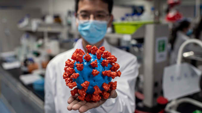 In this picture taken on April 29, 2020, an engineer shows a plastic model of the COVID-19 coronavirus at the Quality Control Laboratory at the Sinovac Biotech facilities in Beijing.