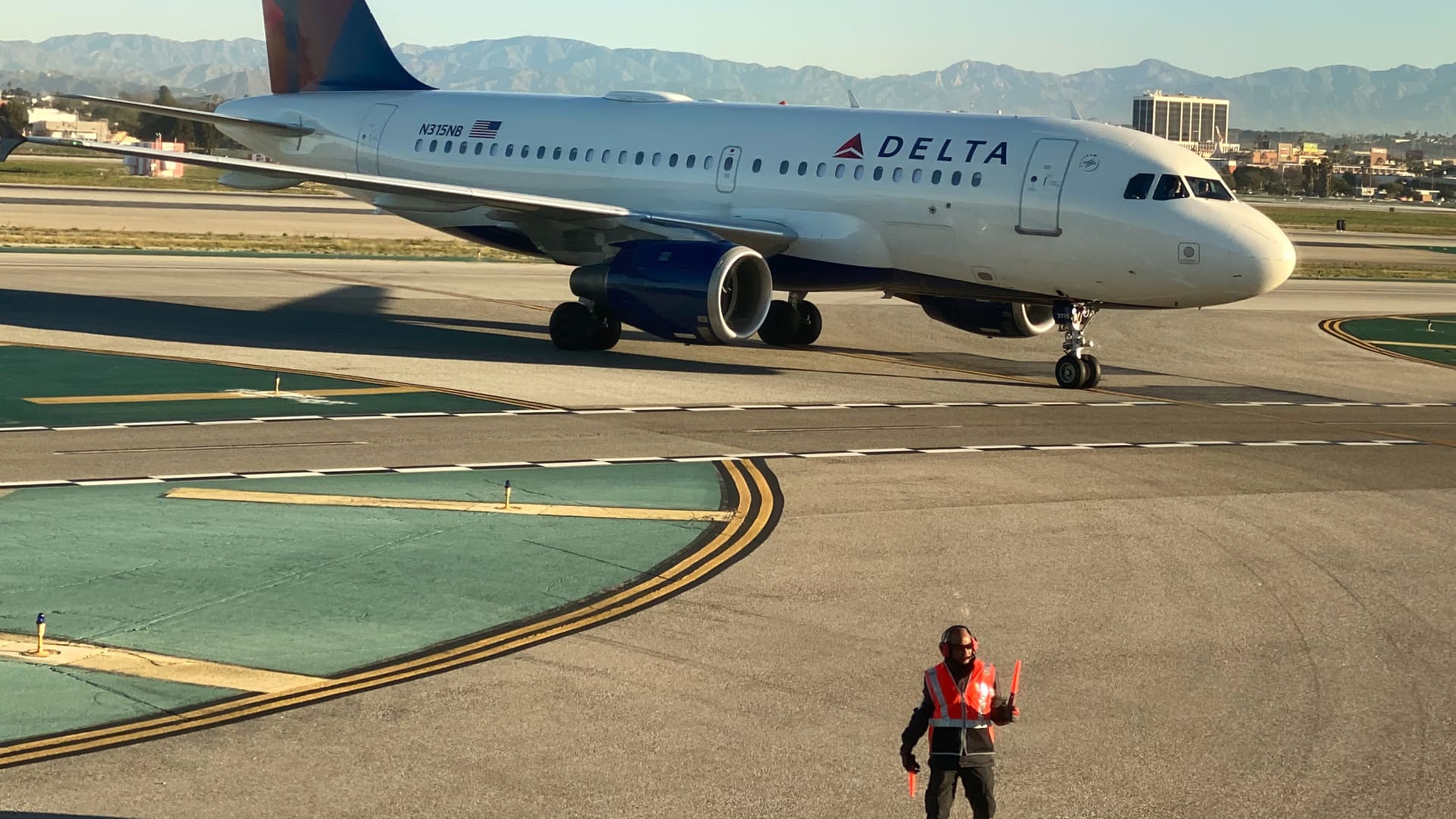 An airport worker guides a Delta Air Lines Airbus A319-100 plane on the tarmac at LAX in Los Angeles, California, U.S., January 6, 2020.