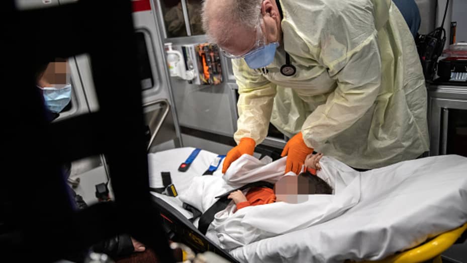 Paramedic Randy Lilly, wearing personal protection equipment (PPE), tends to a 10-month-old boy with fever while riding by ambulance with the infant's mother to Stamford Hospital on April 04, 2020 in Stamford, Connecticut.