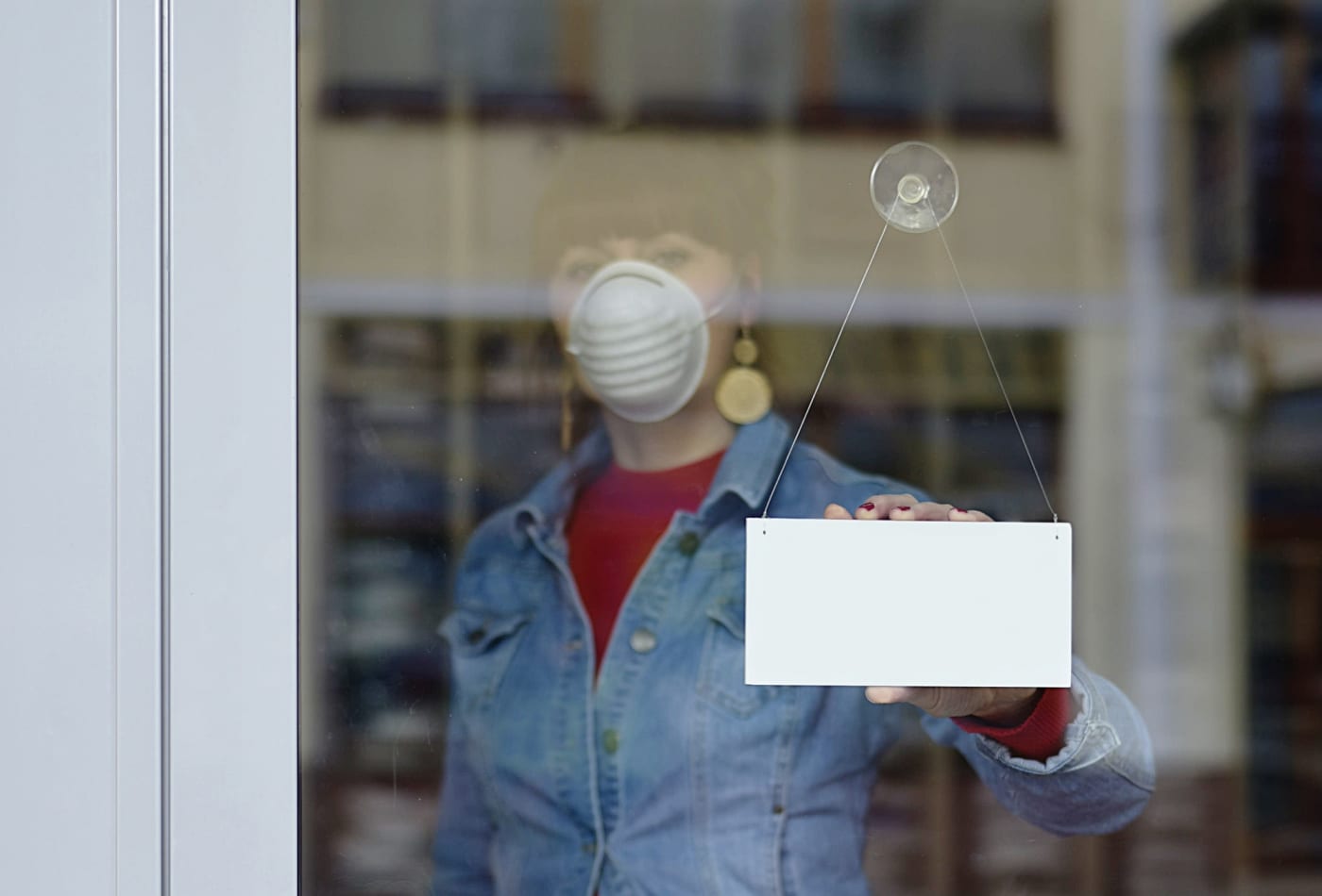 shop keeper with face mask fixing store sign