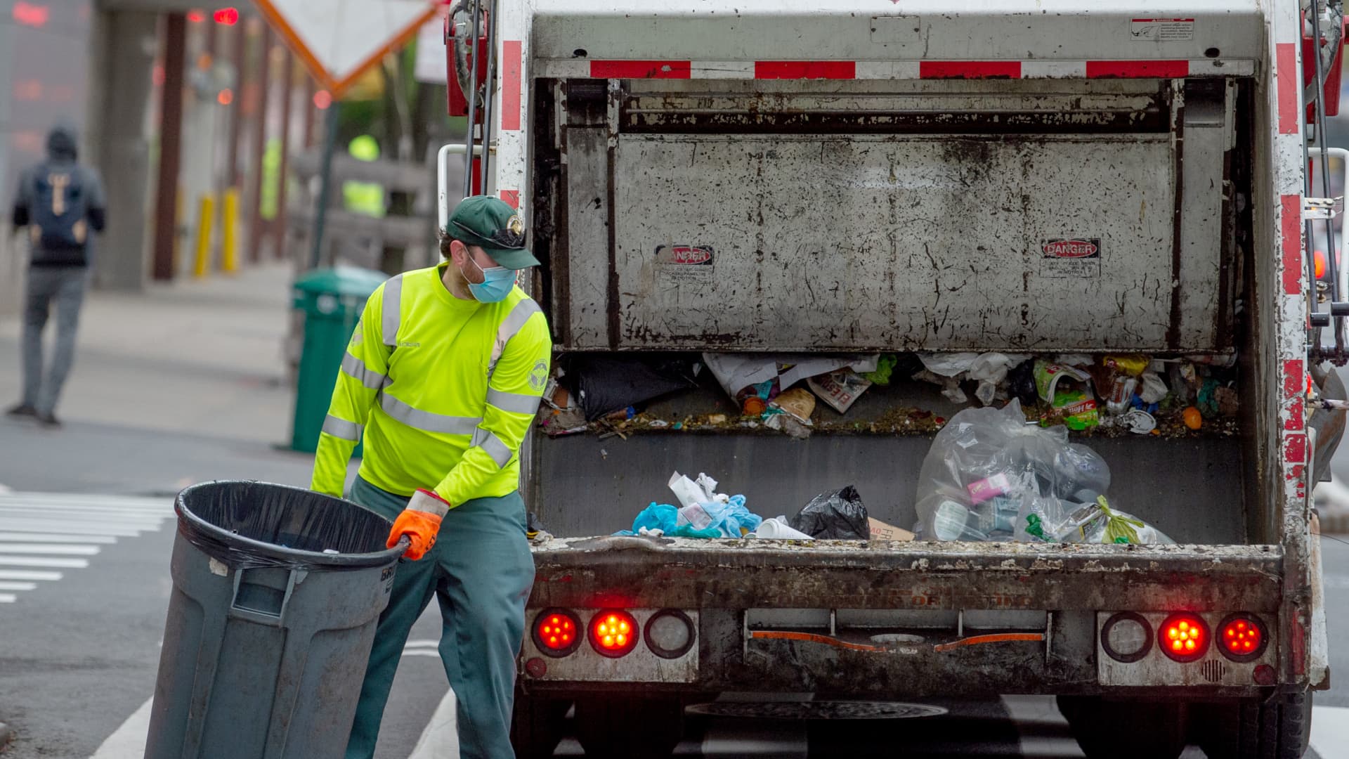 A New York City Department of Sanitation worker wearing a mask and gloves collects the trash amid the coronavirus pandemic on April 30, 2020.