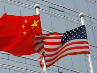 Las banderas nacionales de los Estados Unidos y China ondean fuera de un edificio.