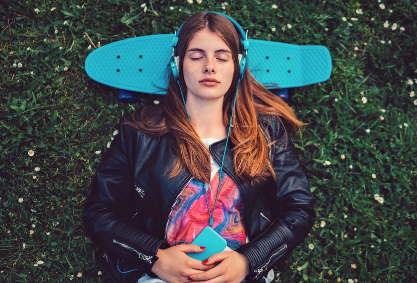 Relaxed teenage girl in the grass listening to music