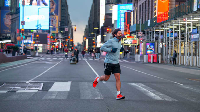 A man wearing a mask runs in an empty Times Square amid the coronavirus pandemic on May 9, 2020 in New York City. COVID-19 has spread to most countries around the world, claiming over 280,000 lives with over 4.1 million cases.