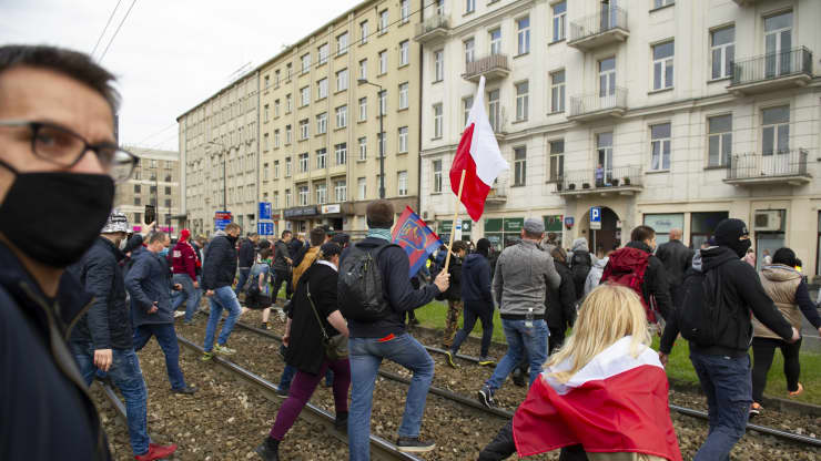 Demonstrators cross the tramway rails during an anti-government protest on May 16, 2020 in Warsaw, Poland. Different social and economic groups took the street to show indignation towards the ruling party PiS (Law &amp; Justice) and to protest against its lawlessness, the restrictions of civil rights and the lack of economic support towards businesses, especially during the Covid-19 pandemic.
