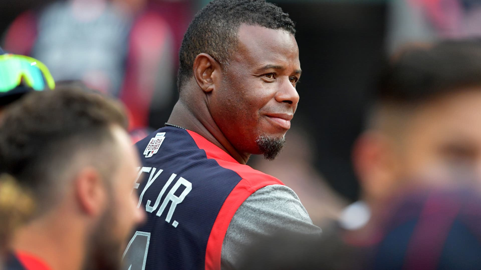 Former MLB star Ken Griffey Jr. talks with players from the dugout of the National League team during the fourth inning against the American league team during the All-Stars Futures Game at Progressive Field on July 07, 2019 in Cleveland, Ohio.
