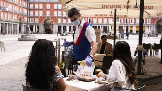 Customers sit at tables socially distanced from each other at the outdoor terrace of a bar, operating at reduced capacity in Plaza Mayor in Madrid, Spain.