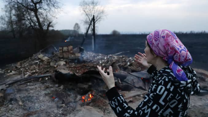 Una mujer cerca de las ruinas de una casa de verano destruida por un incendio en una comunidad de dacha en el distrito de Moshkovo, región de Novosibirsk, en el sur de Siberia.  La región de Novosibirsk está experimentando cientos de incendios que se cree que fueron causados ​​por la quema de hierba vieja.