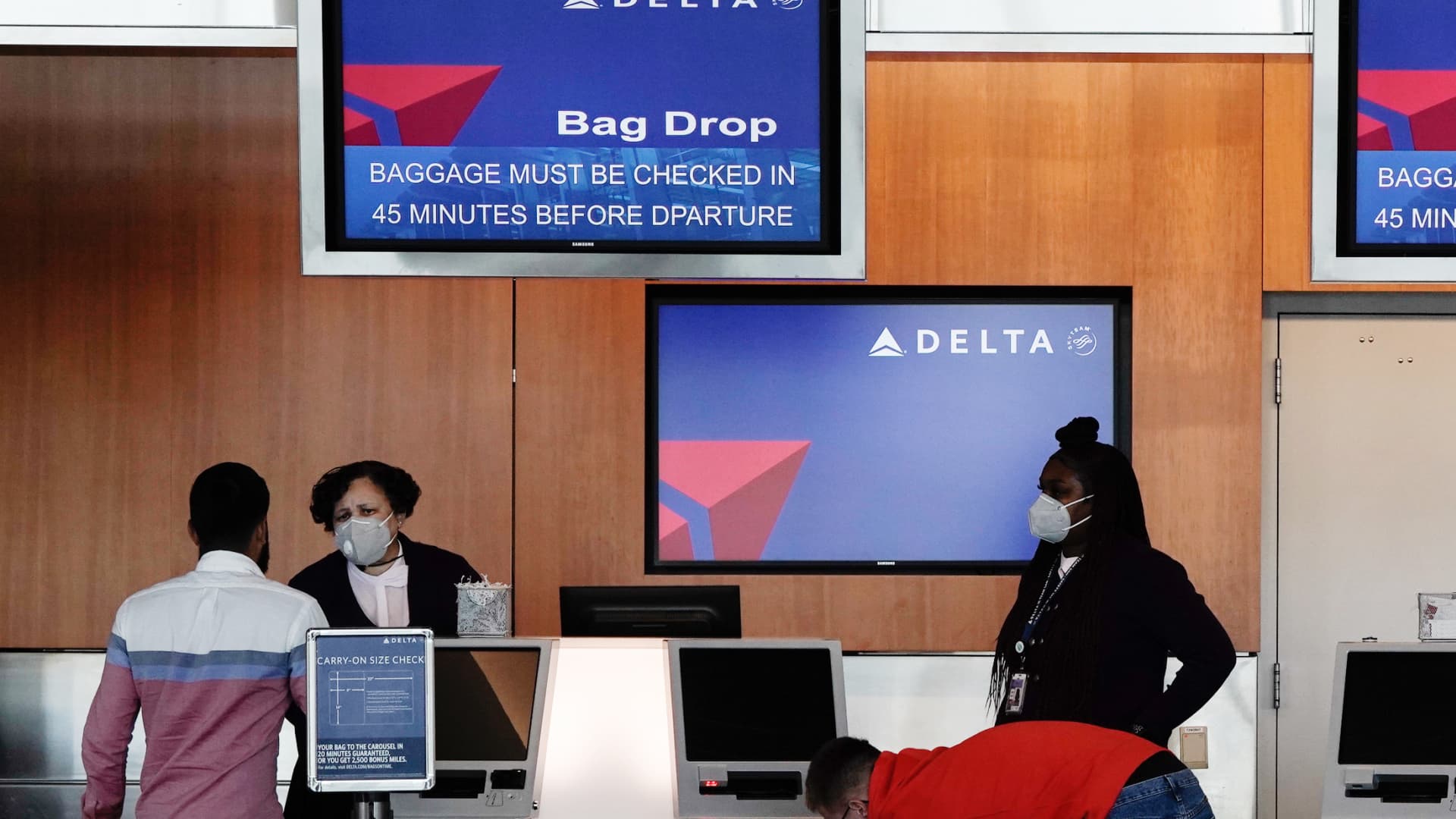 Gate agents assist travelers at a Delta Air Lines Inc. bag drop counter at the San Diego International Airport (SAN) in San Diego, California, U.S., on Monday, April 27, 2020.
