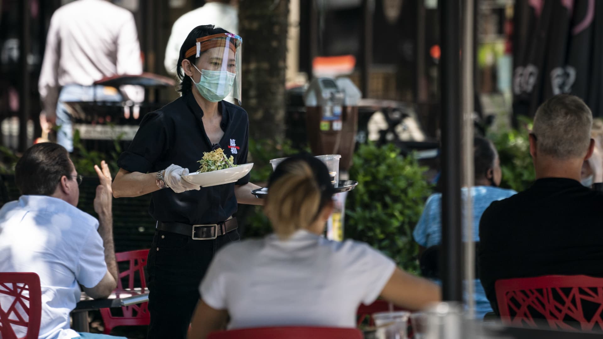 A waiter at Raku, an Asian restaurant in Bethesda, wears a protective face mask as serve customers outdoors amid the coronavirus pandemic on June 12, 2020 in Bethesda, Maryland.
