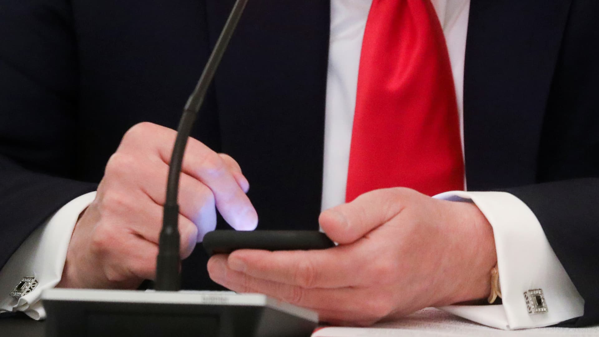 President Donald Trump is seen tapping the screen on a mobile phone at the approximate time a tweet was released from his Twitter account, during a roundtable discussion on the reopening of small businesses in the State Dining Room at the White House in Washington, U.S., June 18, 2020.
