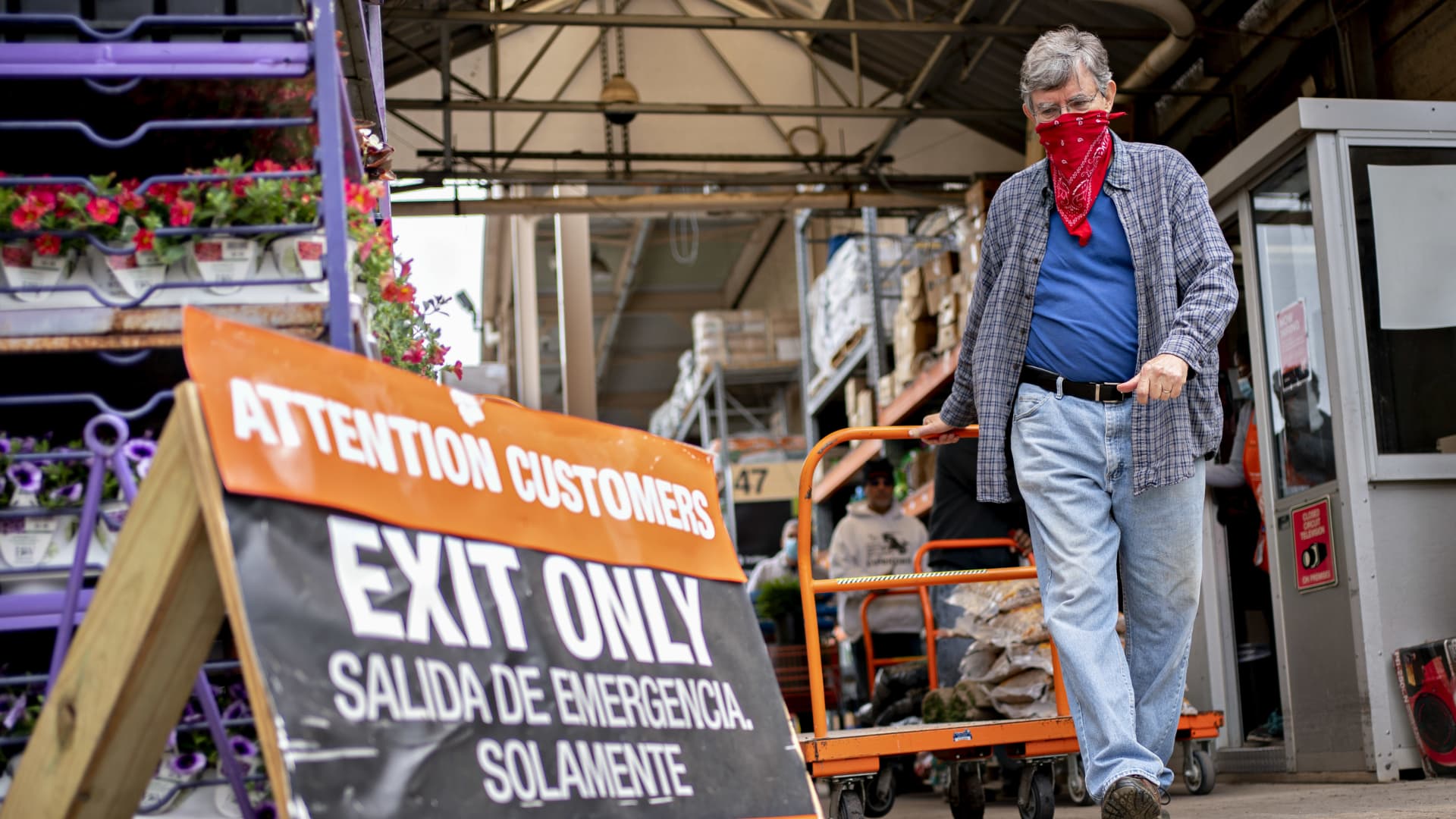 A customer wears a protective mask while pulling a cart outside a Home Depot Inc. store in Reston, Virginia, U.S., on Thursday, May 21, 2020.