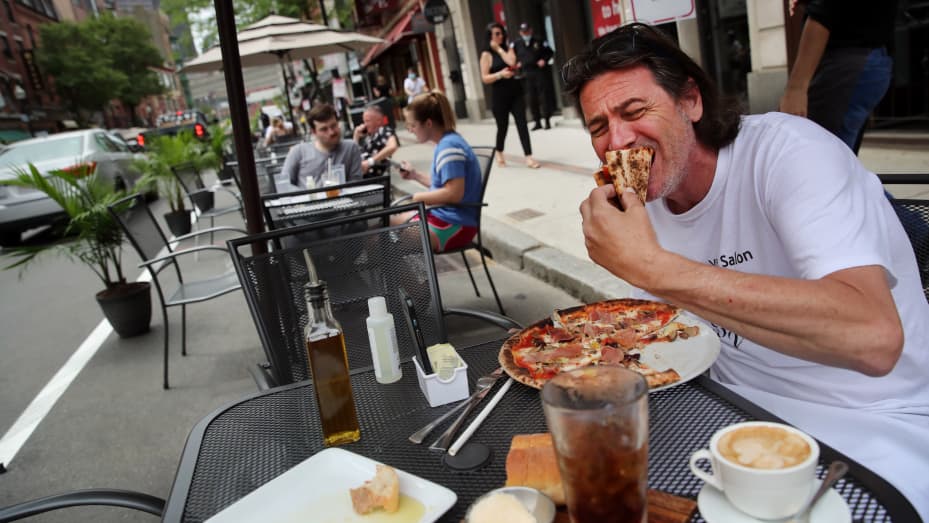 Johnny D'agostina digs into a pizza outside Quattro restaurant on Hanover Street in the North End neighborhood of Boston, MA on June 11, 2020.