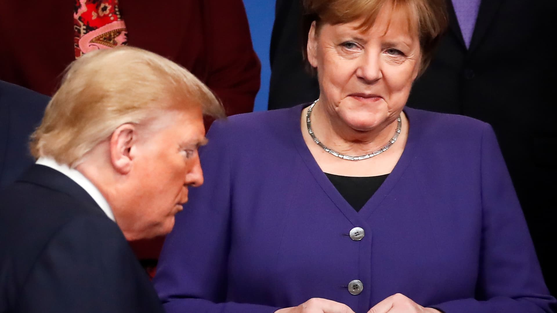 Germany's Chancellor Angela Merkel (R) looks at US President Donald Trump (R) walking past her during a family photo as part of the NATO summit at the Grove hotel in Watford, northeast of London on December 4, 2019.