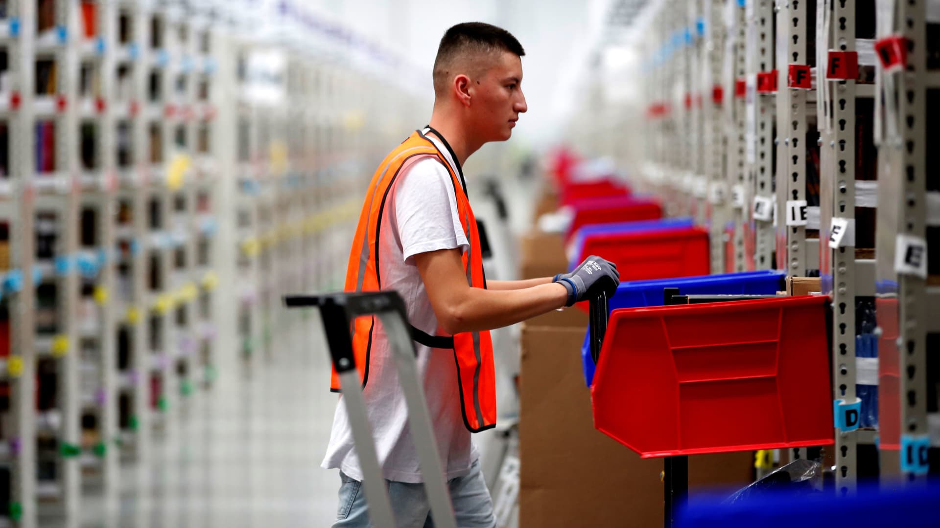 An employee looks for items in one of the corridors at an Amazon warehouse.